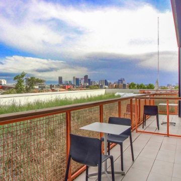 Outdoor patio of Metro City Roofing office with small table and two chairs and view of downtown Denver, Colorado
