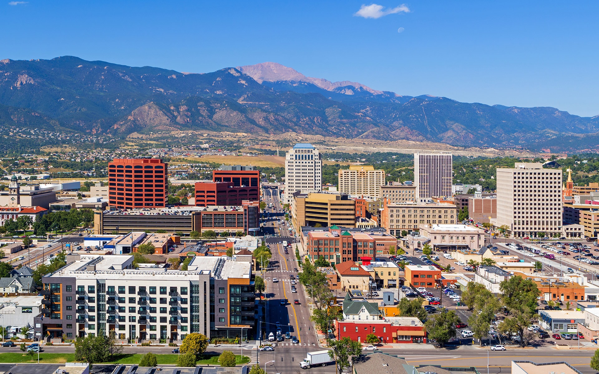 Aerial view of downtown Colorado Springs, Colorado in the foreground with mountains and blue sky in the background