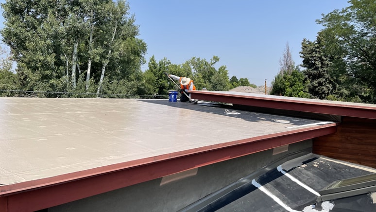 Tan flat roof coating application to a modern home in Denver, CO by Metro City Roofing